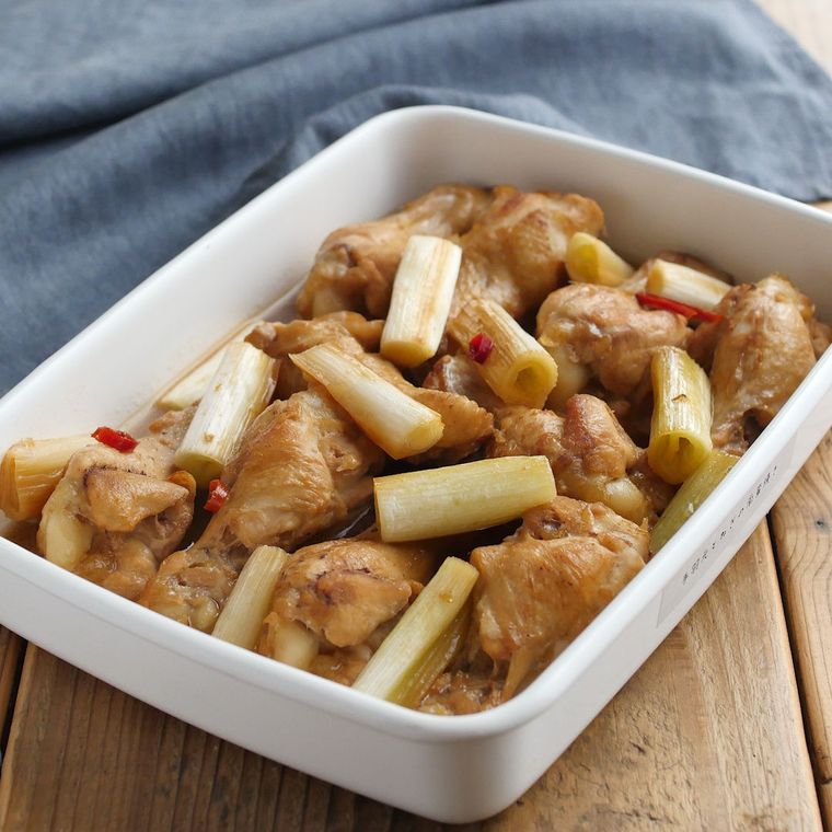 白い保存容器に入っている鶏手羽元と長ねぎの南蛮焼き