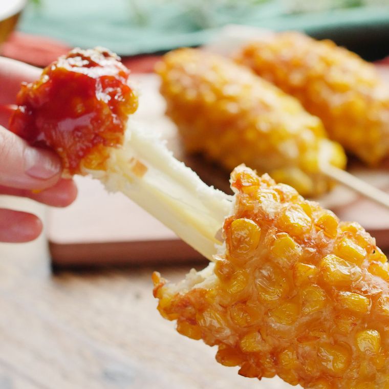 とうもろこしチーズホットドッグを手で割って伸ばした様子