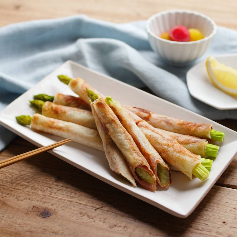 皿に盛られたアスパラガスと生ハムのスティック春巻き