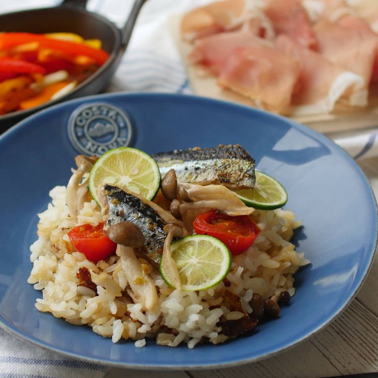 青い皿に盛りつけられた焼きさんまとしめじのパエリア