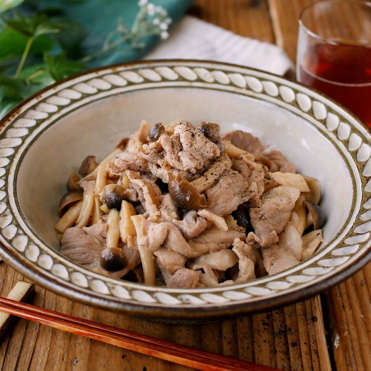 縁取りのある皿に盛りつけられた豚肉としめじのバタポン炒め