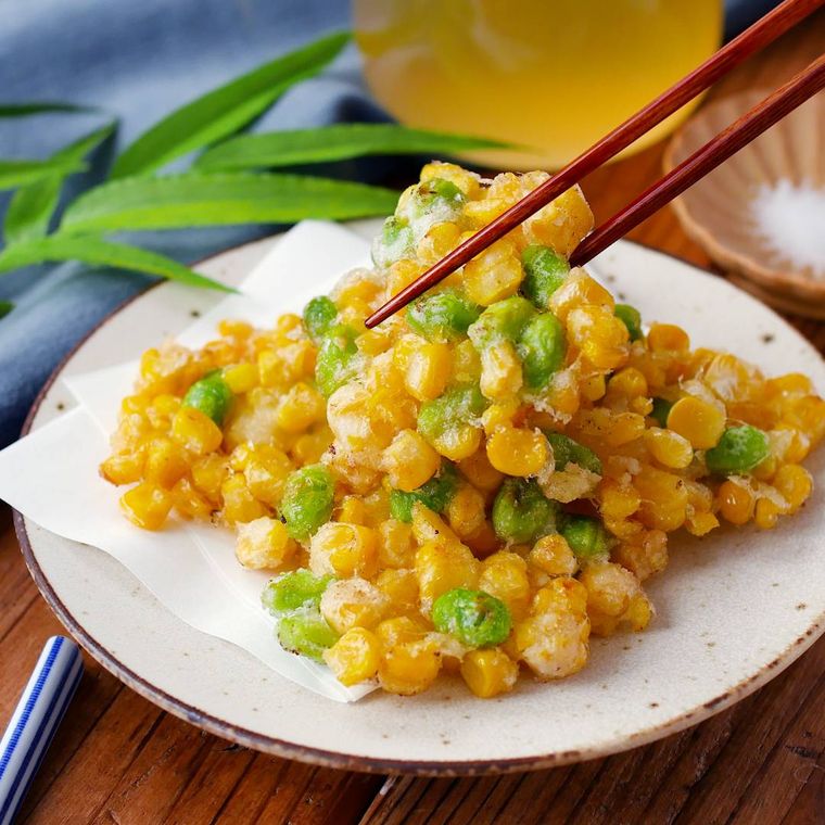 とうもろこしと枝豆のかき揚げを箸で持ち上げている