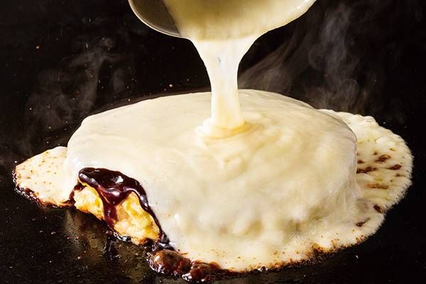 お好み焼きの上に溶けたチーズをかけている