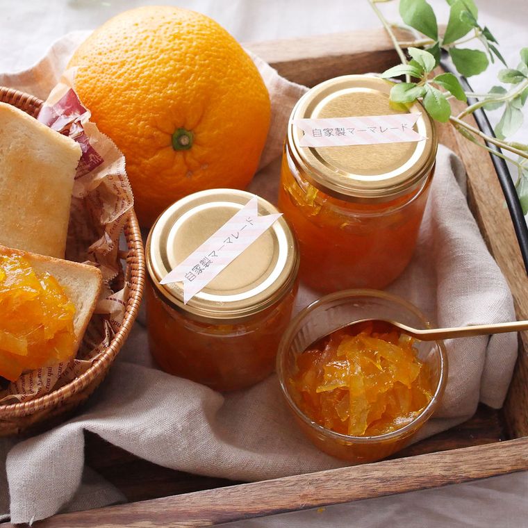 瓶詰めにされたマーマレードとカップ入りのマーマレード、甘夏などが木製トレーの上に置かれている