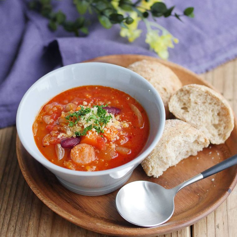 ミネストローネとパンが木のお盆に置かれている