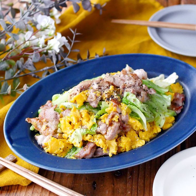 青い皿に盛られたキャベツと豚バラ肉と卵の炒め物