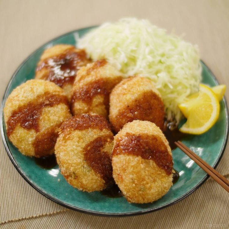 緑色の皿に盛られたコロッケと千切りキャベツ