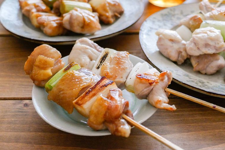 焼き鳥が2本のっている小皿がある食卓