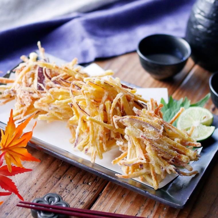 紙を敷いた黒色の長皿に盛られたさつまいものかき揚げ