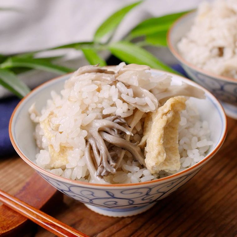 白地に青い模様入りの茶碗に盛り付けた、まいたけと油揚げの炊き込みごはん