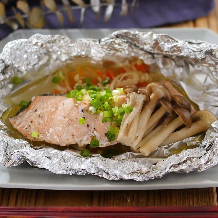 白い皿にのっている鮭と玉ねぎとしめじのホイル焼き