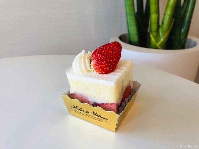 白いテーブルの上にのる正方形をした苺ショートケーキ