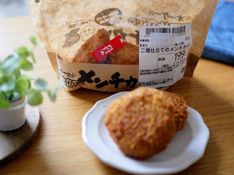 白い小皿にのったオーケーストアの二層仕立てのメンチカツと奥にパッケージが見えている様子