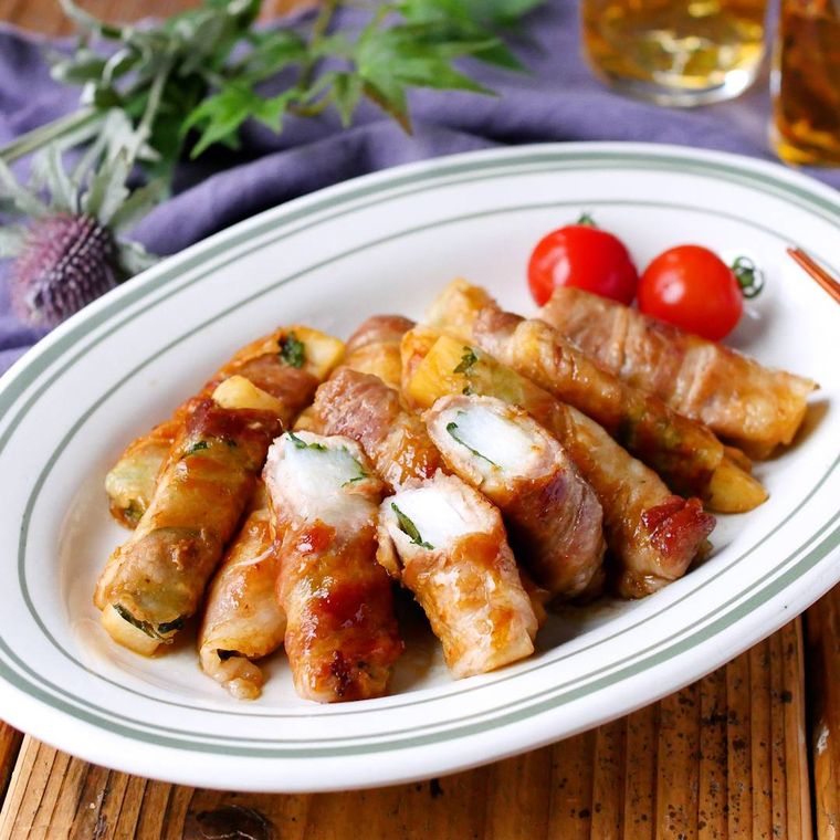 縁取りのある皿に盛りつけられた肉巻き長芋のポン酢炒め