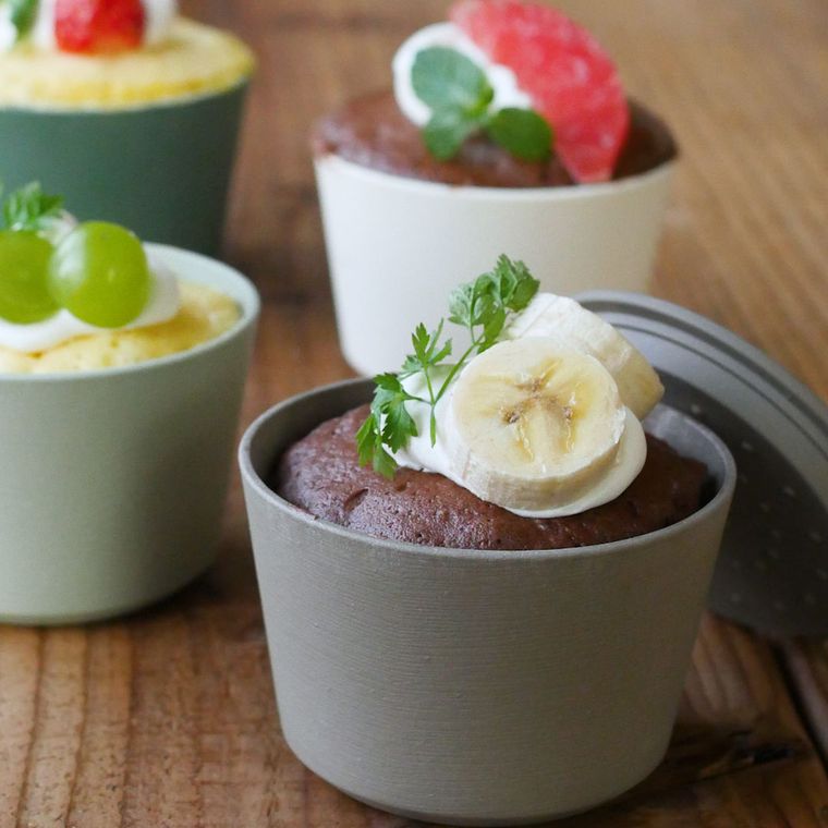 耐熱容器に入ったバナナやぶどうをトッピングしたカップケーキ
