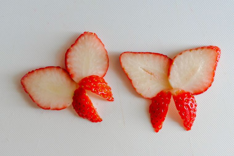 いちごを蝶のように盛り付けたものが2つ並ぶ白いまな板