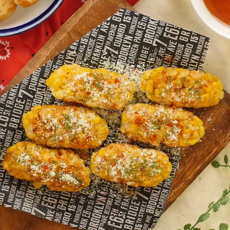 英字の紙を敷いた木製のボードに並んだはんぺんとコーンの粒々とうもろこし揚げ