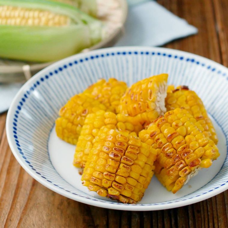 青色の模様が入った白色の深皿に盛られた焼きとうもろこし