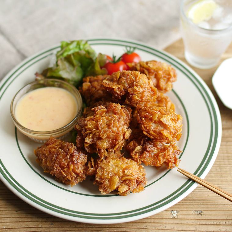 緑の縁取りの皿に入った、クリスピーチキンとチリマヨソース