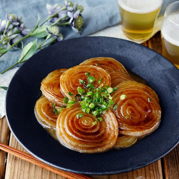 黒い皿に盛られた新玉ねぎの照り焼きステーキ