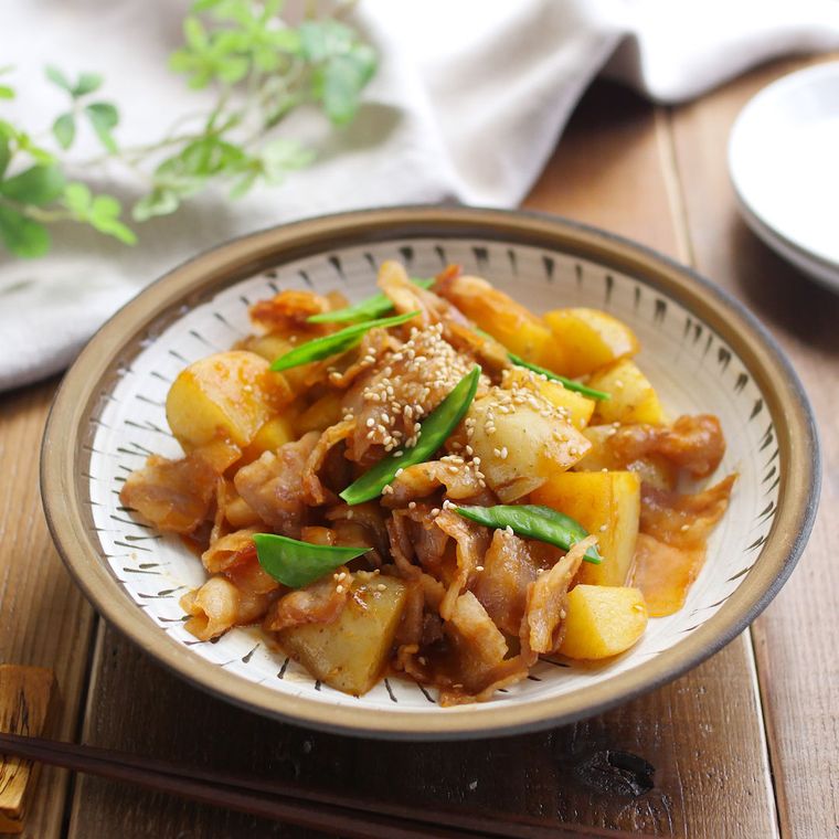 茶色の丸皿に盛られたじゃがいもと豚バラのコチュジャン炒め