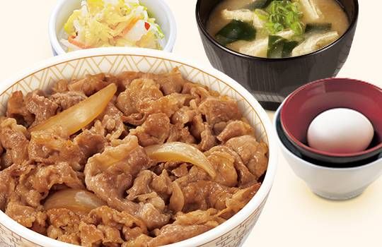 牛丼、味噌汁、お新香、卵が置かれている
