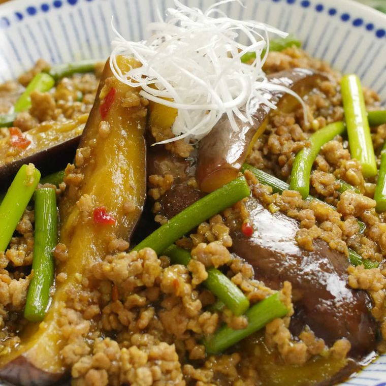 白に青い模様の皿に盛りつけられたにんにくの芽となすのカレー麻婆