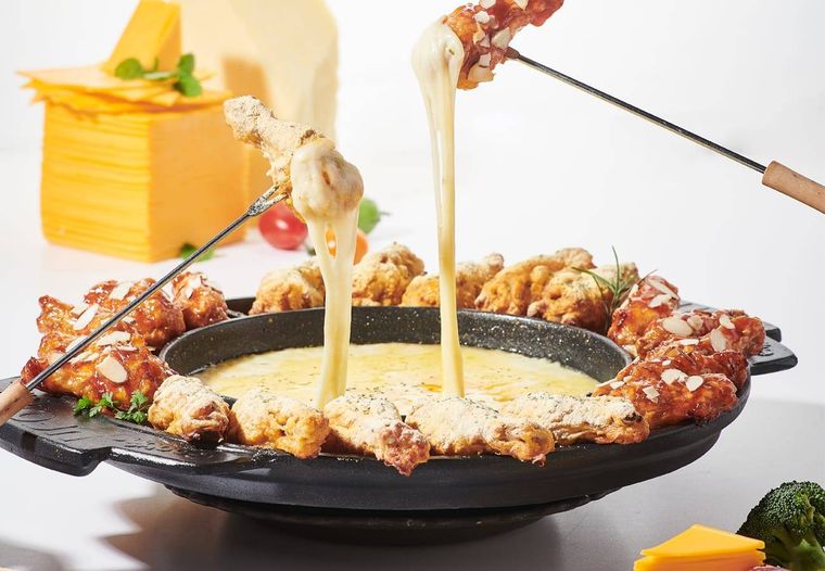 フライドチキンをチーズにくぐらせている