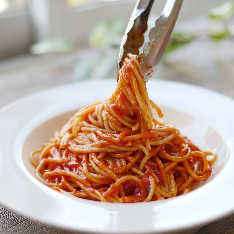 皿にトマトパスタを盛り付けている