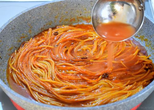 フライパンの中のパスタにトマトだしを注いでいるところ