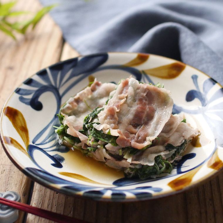 模様入りの皿に盛りつけられた豚バラ肉と水菜の重ね蒸し