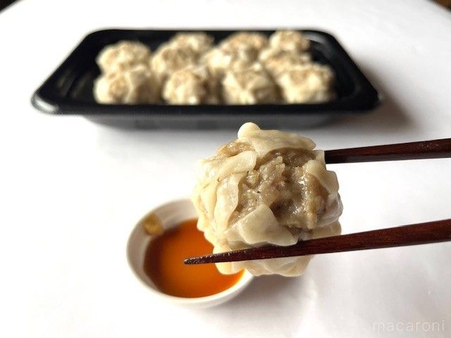 大きな焼売をカラシしょうゆで食べようとしている