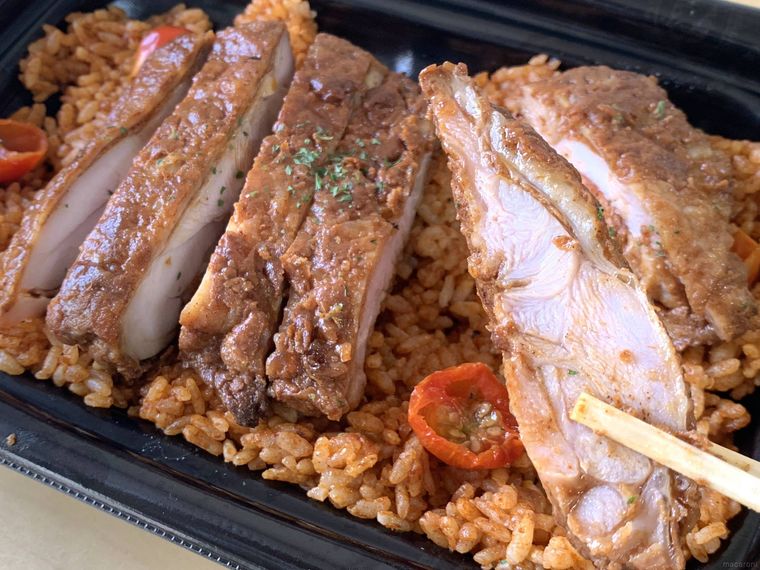 ロピアのお弁当ジャンバラヤのチキンを箸で持ち上げる様子