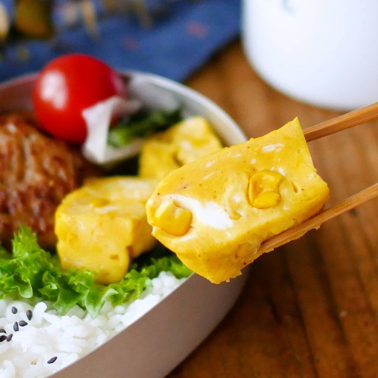 お弁当箱から持ち上げられるコーンスープ卵焼き