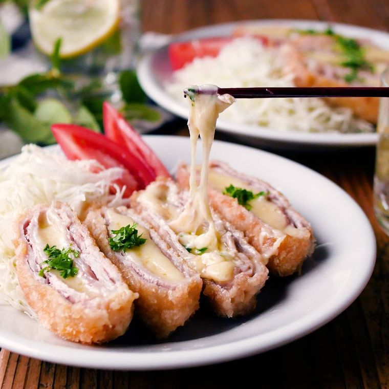 皿に盛られたチーズとんかつ、千切りキャベツ、トマト