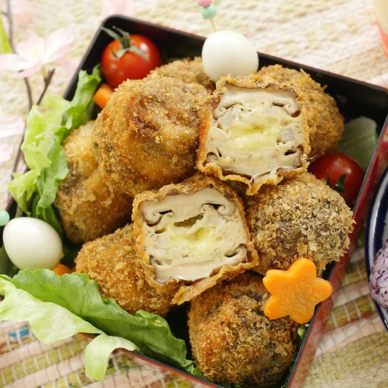 お弁当箱に入ったしいたけの肉詰めフライ、数種類の野菜、うずら卵