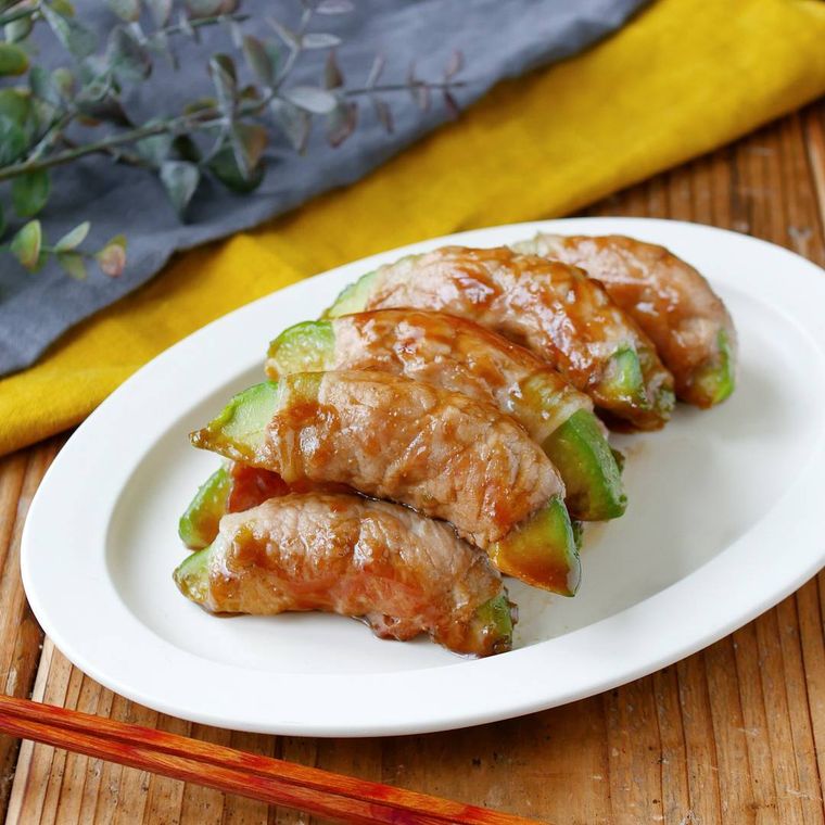 白い楕円の皿にアボカドの肉巻きが盛り付けてある