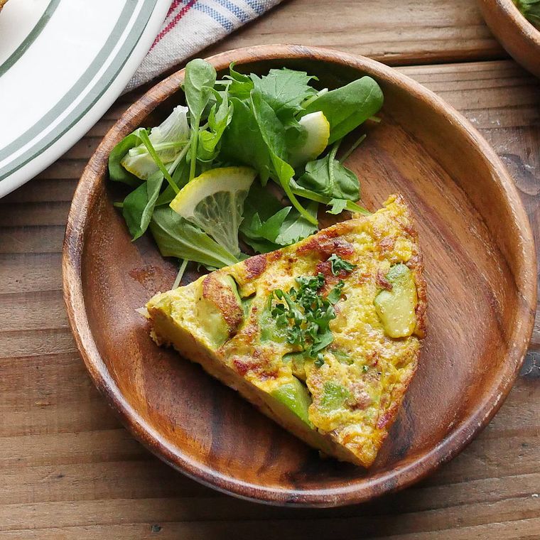 木の皿にアボカドのスパニッシュオムレツと野菜が盛り付けてある