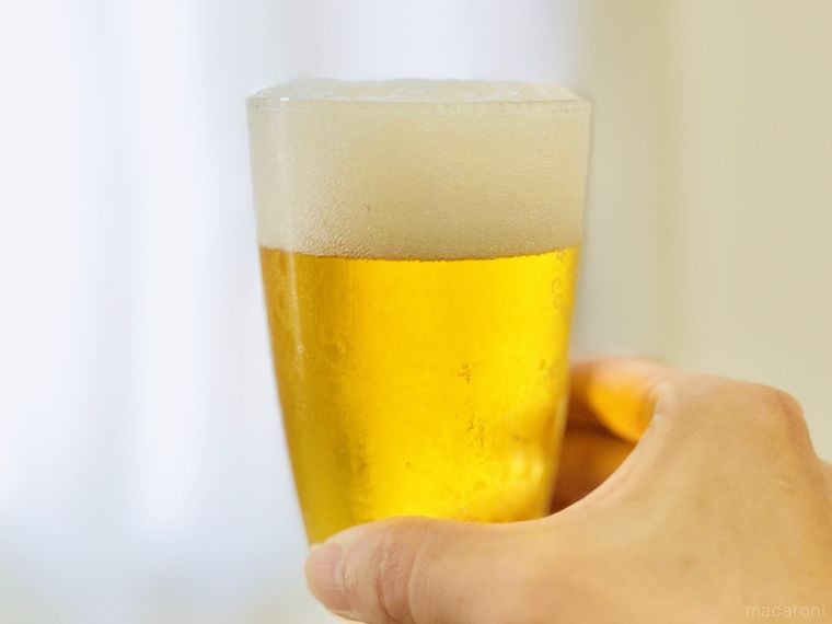 ドン・キホーテのラガービールが入ったグラスを持ち上げている様子