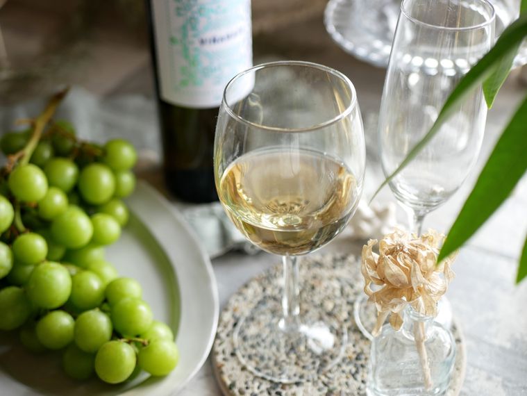 グラスに入った白ワインとブドウ