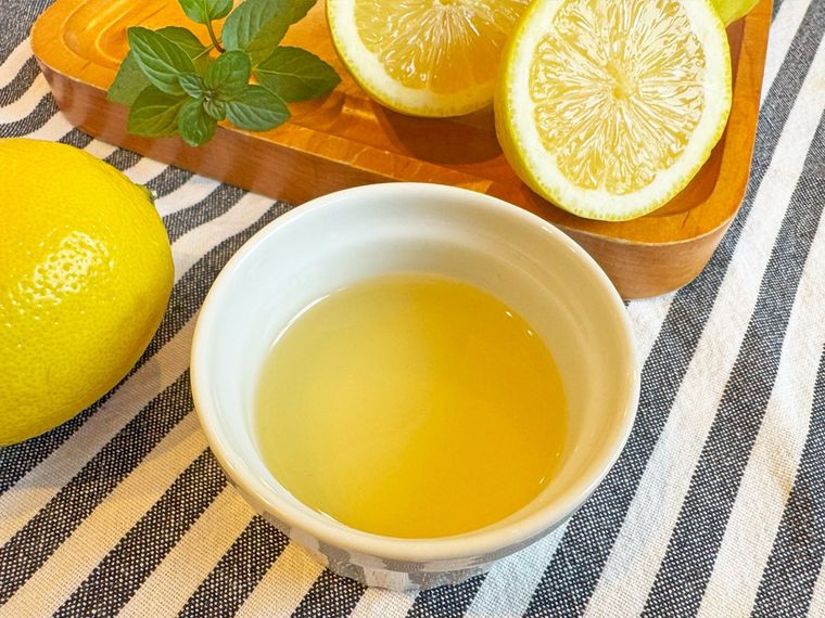 白い器に入ったレモン果汁と、まな板の上に乗った輪切りのレモン、ミント