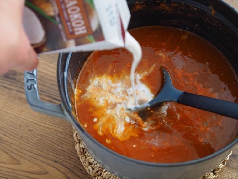 ココナッツミルクを鍋に注ぎ入れる様子