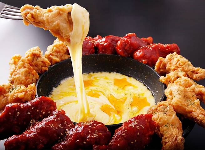 溶けたチーズにフライドチキンをくぐらせている