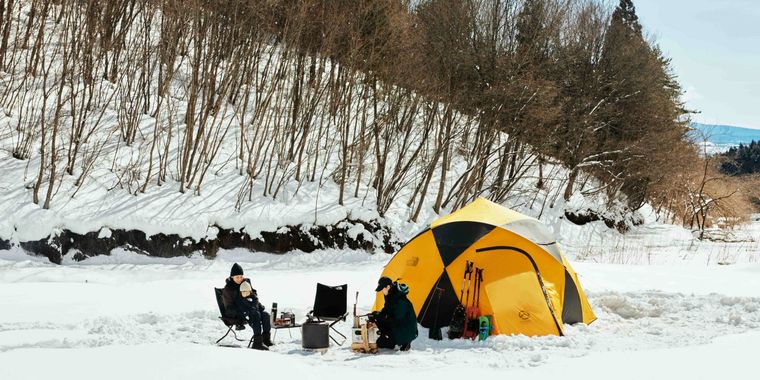 雪が積もった大地に黄色いテントが設営されている