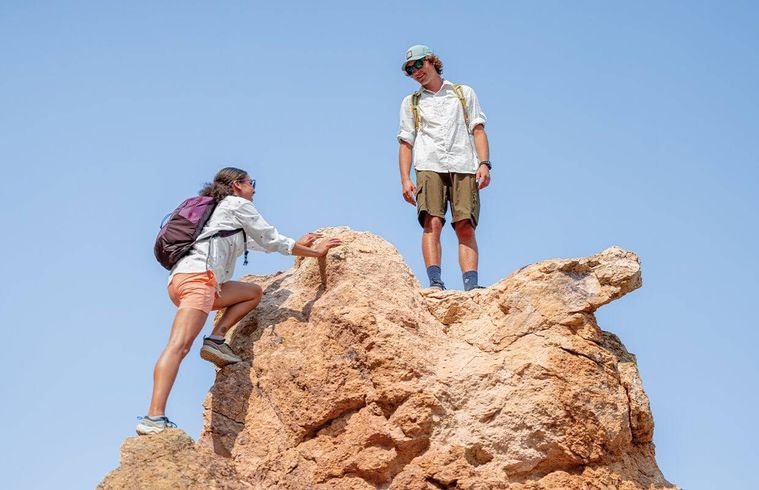 コロンビアのウェアを着た男女が岩に登っている