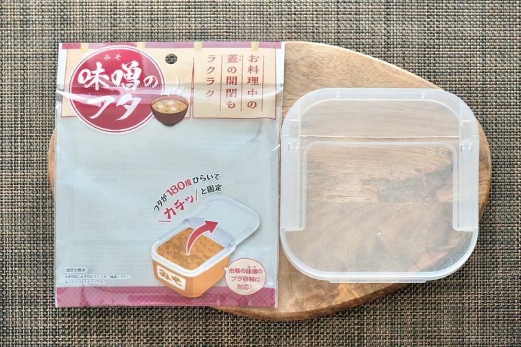 ウッドプレートに置かれたダイソーの味噌のフタ