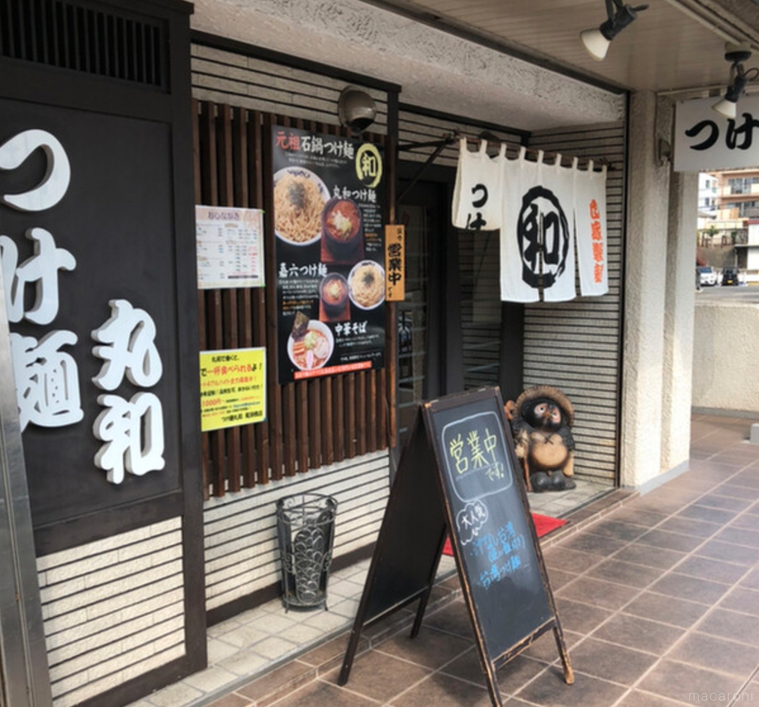 白い暖簾、たぬきの置き物がある外観