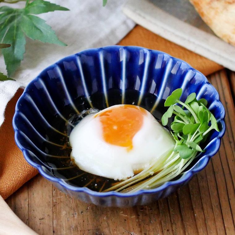 青い器に盛られた温泉卵にかいわれ大根が添えられている
