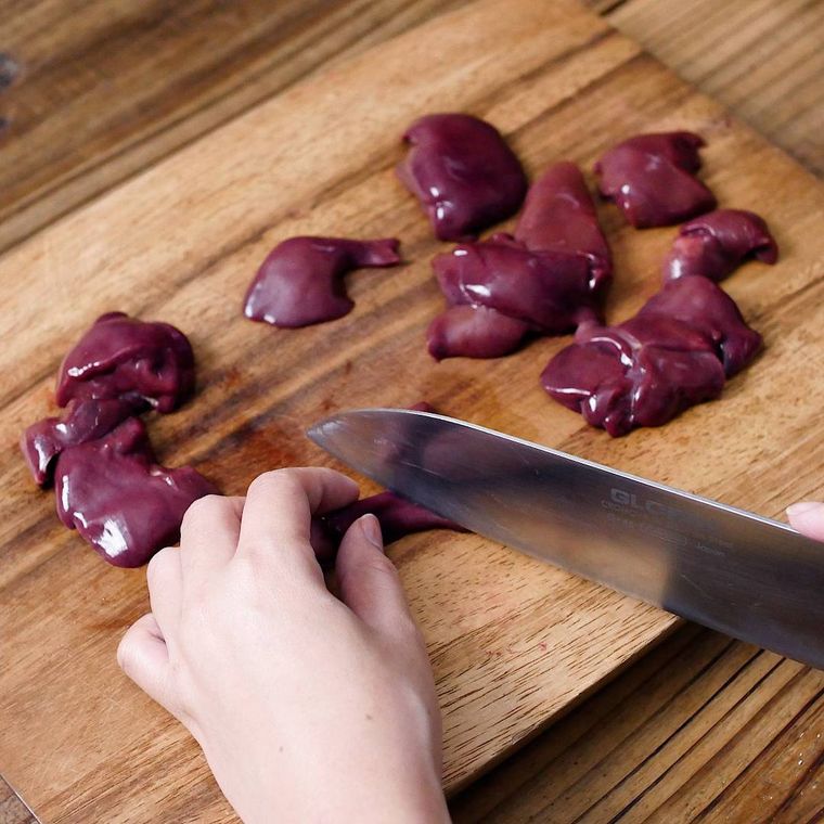 まな板の上で生のレバーを切っている様子