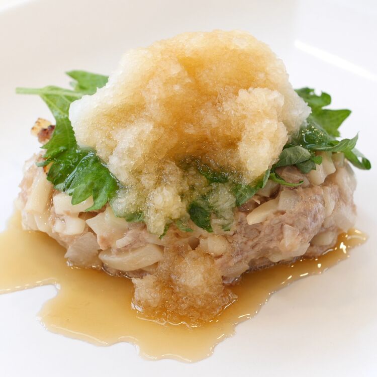 うどんハンバーグが白い皿に盛り付けられているところ